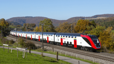 A Swiss Federal Railways (SBB) double- decker train traveling through a scenic landscape, showcasing modern rail technology, digitalization, and predictive maintenance solutions