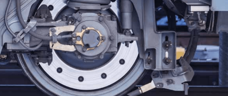 Close-up of a railway axlebox and suspension system, showcasing intricate mechanical components used for predictive maintenance and digital tracking