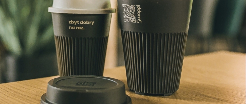 A close-up shot of black, reusable food containers from Swapp! with a visible QR  code for tracking.