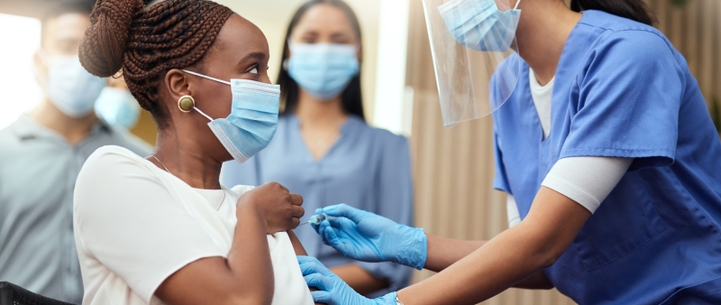 girl taking a vaccine and surrounded by nurses